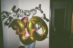 a woman holding two large balloons in front of her face and the words happy on it