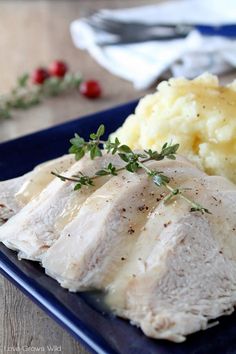 a blue plate topped with meat and mashed potatoes on top of a wooden table