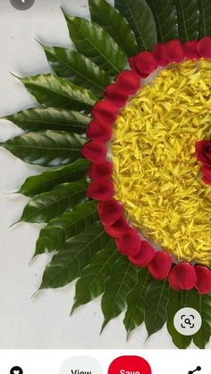 a flower arrangement made out of yellow and red flowers on top of green leafy leaves