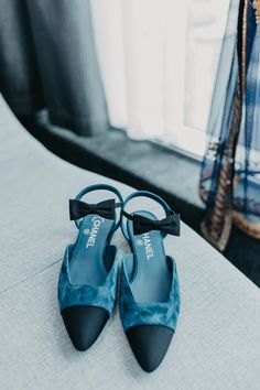 a pair of blue high heeled shoes sitting on top of a white bed next to a window