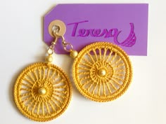 a pair of yellow earrings sitting on top of a purple card