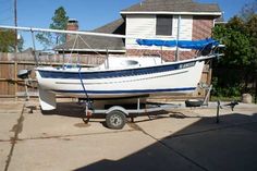 a boat is parked on the trailer in front of a house with a blue and white stripe