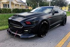 the black mustang is parked on the side of the road