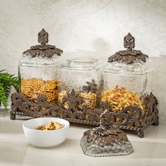 two glass jars filled with food sitting on top of a counter next to a bowl