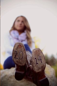 a woman sitting on top of a rock next to a pair of shoes with the number fourteen