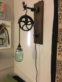 an old fashioned wall light with a mason jar hanging from it's side on the wall