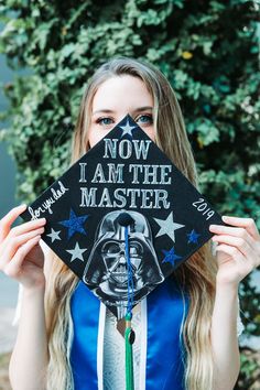 a woman holding up a graduation cap with the words now i am the master on it