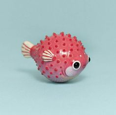 a red and white toy fish sitting on top of a blue surface with one eye open