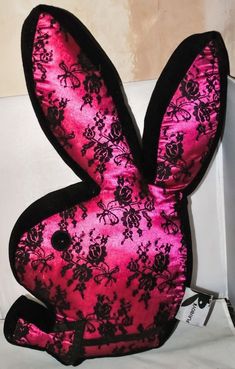 a pink and black stuffed rabbit sitting on top of a bed