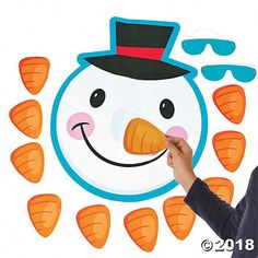 a man holding up a paper cut out of a snowman with carrots around it