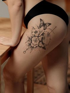 a woman's thigh with flowers and a butterfly tattoo on her lower half leg