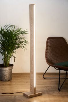 a wooden floor lamp next to a chair and potted plant