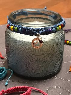 a glass jar sitting on top of a table covered in bracelets and other items