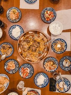 a wooden table topped with blue and white plates filled with food