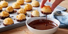 someone dipping some kind of dessert into a bowl with chocolate sauce on the table next to it