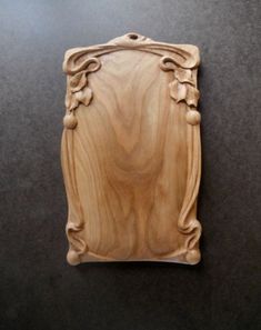 a wooden plaque with an ornate design on the front and sides, sitting on a black surface