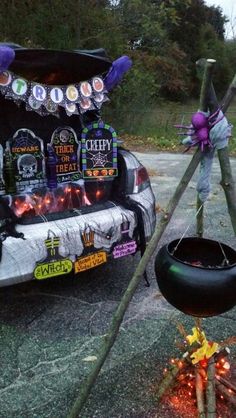 a car with decorations on the hood parked next to a fire pit and some sticks