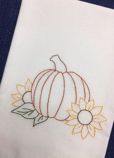 an embroidered pumpkin and sunflower on a white towel