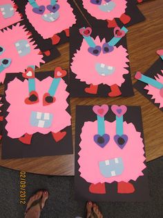 some pink and blue paper cut outs on a wooden table with someone's feet