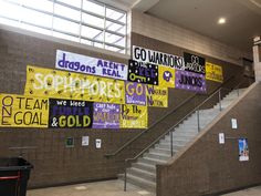 several banners are hanging on the wall in front of some stairs