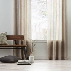 a wooden bench sitting in front of a window with curtains on the windowsills