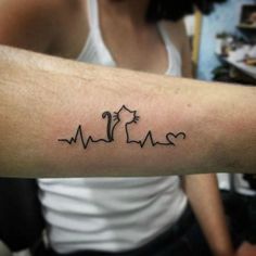 a person with a tattoo on their arm that has heartbeats and an arrow in the shape of a cat