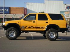 a yellow pick up truck parked in a parking lot