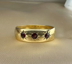 A beautiful German solid 14k yellow gold band with three garnets, a timeless classic vintage band that will always look great! This 1950s vintage ring is signed 14k (585) + maker's mark (antlers punch). There's plenty of room inside to add your own engraving. A nice heft of the 6.3 grams of gold, 6 mm wide, US size 10 1/4 (EU 63) - sizing it could be easily done by your jeweler if needed. Would make a nice gift for someone special! Material: 14k yellow gold (hallmarked) Total weight: approx 6.3g US size: 10 1/4 (EU 63) Measures: 21 mm in diameter, band is 6 mm wide Memento Mori Ring, Garnet And Gold, Us Size 10, Red Band, Antique Engagement Rings, Vintage Band, Maker's Mark, Art Deco Ring, Religious Jewelry