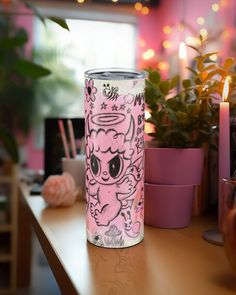 a pink tumbler sitting on top of a wooden table next to potted plants