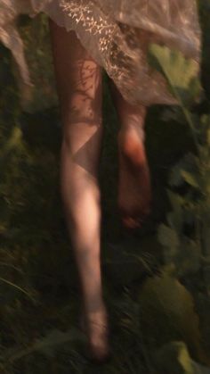 a woman walking in the grass with her legs spread out and wearing sheer stockings on