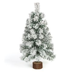 a small white christmas tree sitting on top of a wooden stump in front of a white background