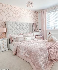 a bedroom decorated in pink and white with a bed, nightstands, mirror and window