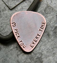 a metal guitar pick with the words i do rock you every time on it