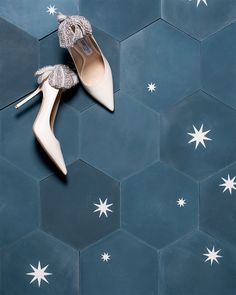 a pair of white high heeled shoes sitting on top of a blue tiled floor