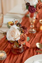 the table is set with white and red flowers in vases, silverware, and candles