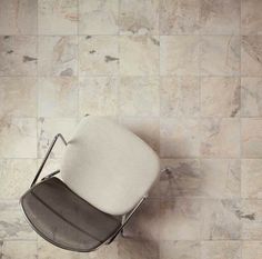 a white chair sitting on top of a wooden floor next to a wall covered in tiles