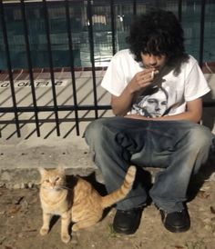 a man sitting on a bench next to a cat