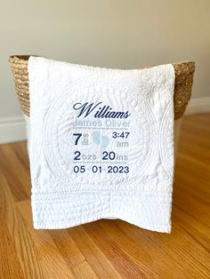 a baby's birth blanket on top of a basket with the date printed on it