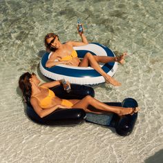 two women in yellow swimsuits sitting on an inflatable raft and drinking water