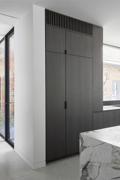 a kitchen with black cabinets and marble counter tops in front of a large sliding glass door