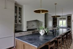 a large kitchen with marble counter tops and bar stools in front of the island