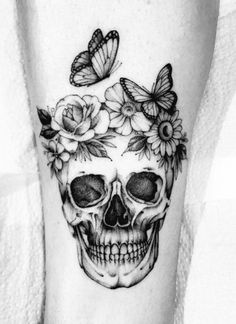 a skull with flowers and butterflies on it's head is seen in this tattoo