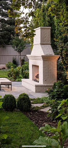 an outdoor fireplace in the middle of a garden