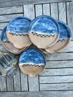 four blue and white plates sitting on top of a wooden table