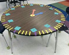 a table with several chairs around it and a clock painted on the surface in different colors