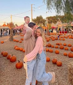 a man and woman standing in front of pumpkins