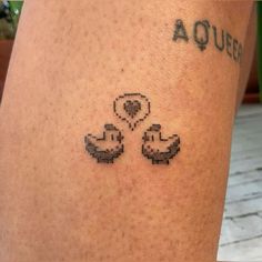 a small tattoo on the leg of a person with two ducks in front of them