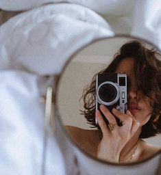 a woman taking a selfie in the mirror while she is holding her camera up to her face