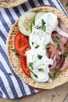 two pita sandwiches with cucumbers, tomatoes and onions on top are sitting next to each other