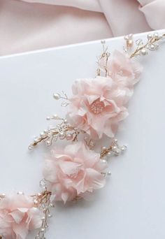 three pink flowers are on top of a white surface with pearls and beads in the middle